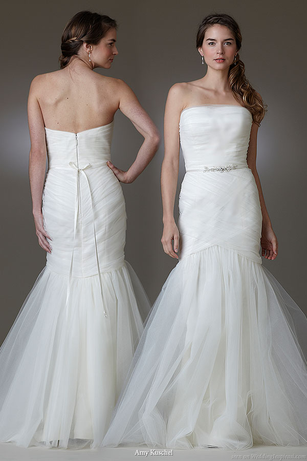 Viva wedding dress by Amy Kuschel made with layers of soft tulle, dramatic strapless trumpet silhouette features a hand draped bodice and wrap style upper skirt with a stunning flared hemline, waistline adorned with crystal embellished belt