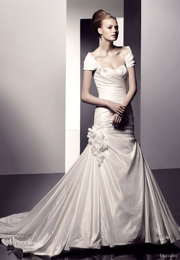 Esme wedding dress, mermaid silhouette with strapless sweetheart neckline with Swarovski crystal and precious stone bow applique on bust. Rouched bodice and floral detail with bugle beads on side. From Enzoani 2010 bridal gown collection