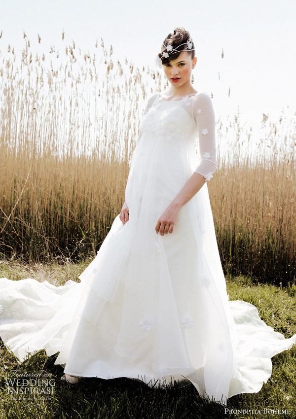 Pronuptia 2011 wedding gowns: Flower de bohème - sublime volume elfin dress in ivory gazard richly strewn with tone on tone flowers. The heart-shaped décolleté, the arms and the shoulders are veiled by a fine lycra tulle, also flowered. The back is closed by crystal buttons. Under the gazard's transparency a fine A-shaped silhouette in mat satin takes shape.